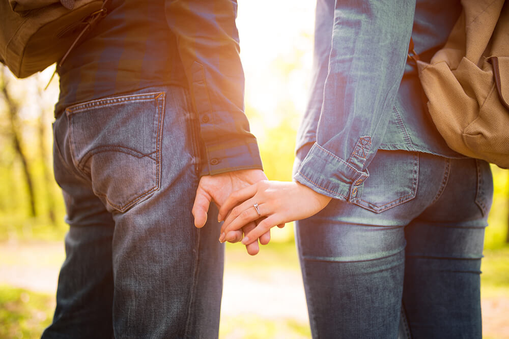 Couple loosely holding hands, wedding band